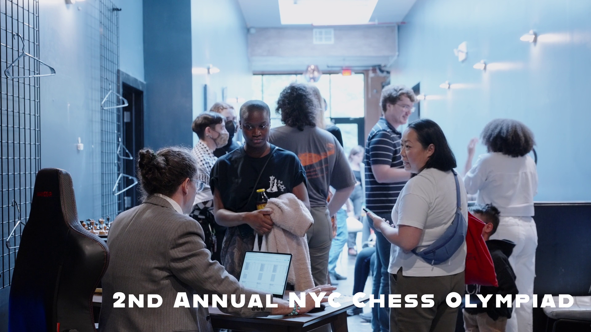 2nd Annual NYC Chess Olympiad title card over a crowd scene