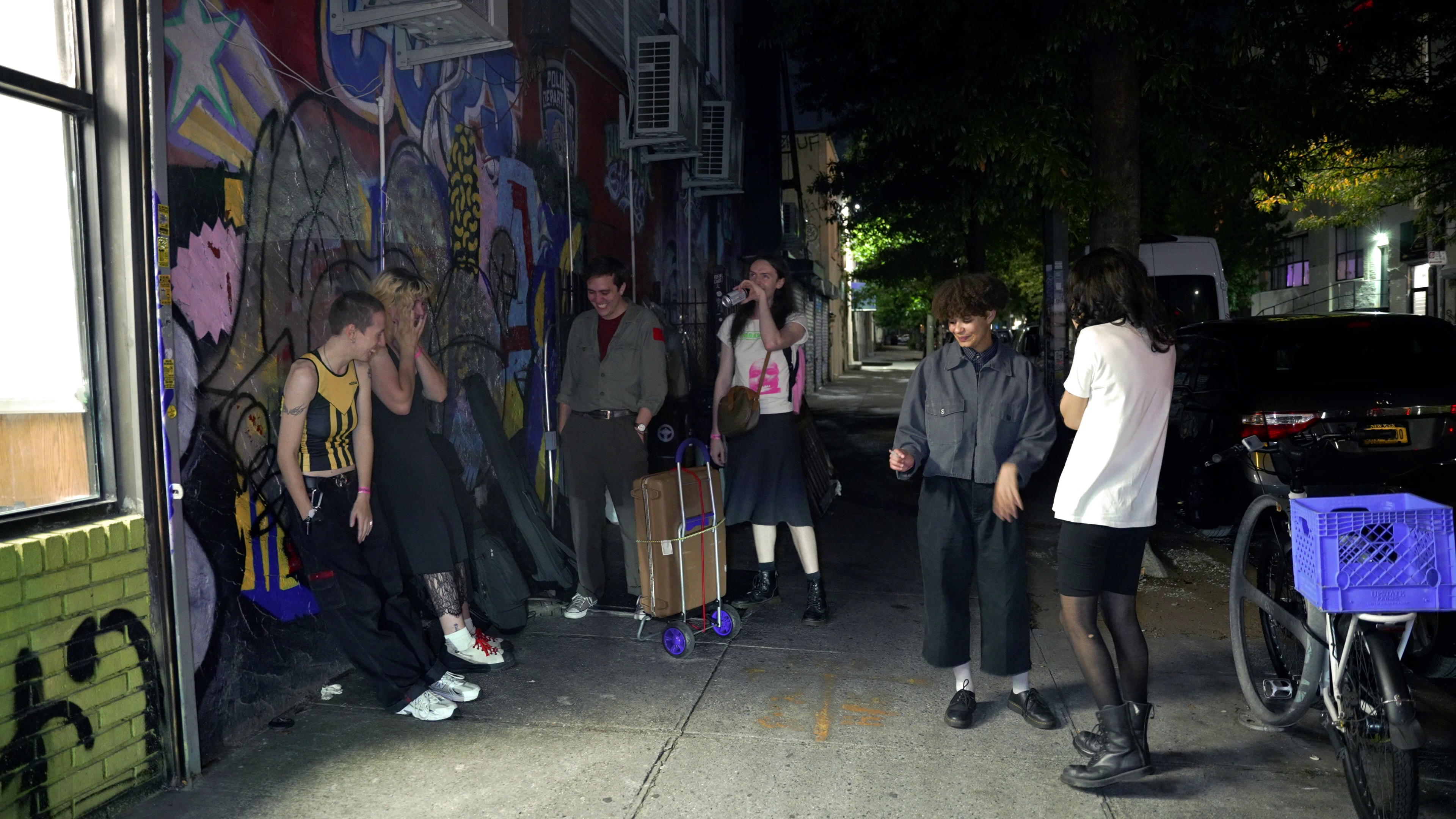 Band members gathered on a graffiti-covered street at night