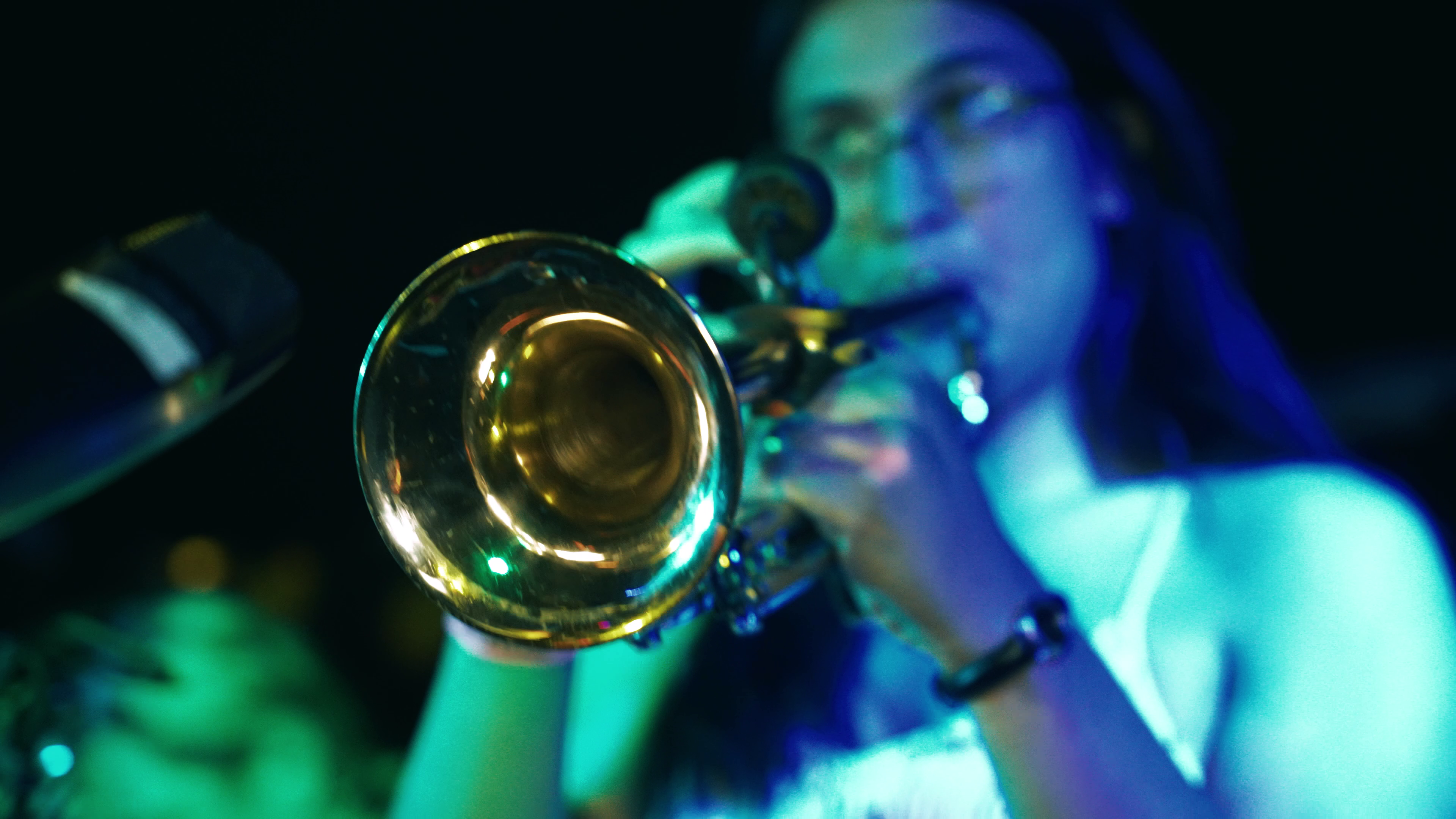 A trumpet player lit in blue and teal